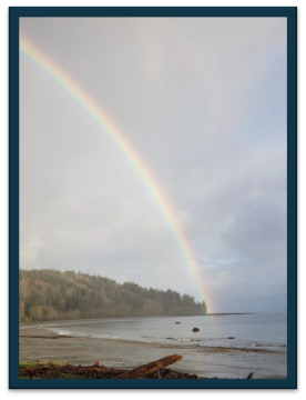 A rainbow at the beach - sandy beach, calm ocean and a tall rainbow at the end of the jetty. 